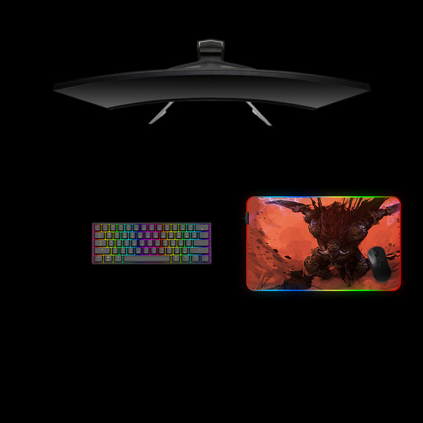Gaming desk setup with a medium size RGB lit mouse pad featuring an Elden Ring Radahn design, keyboard, and monitor on a black background.